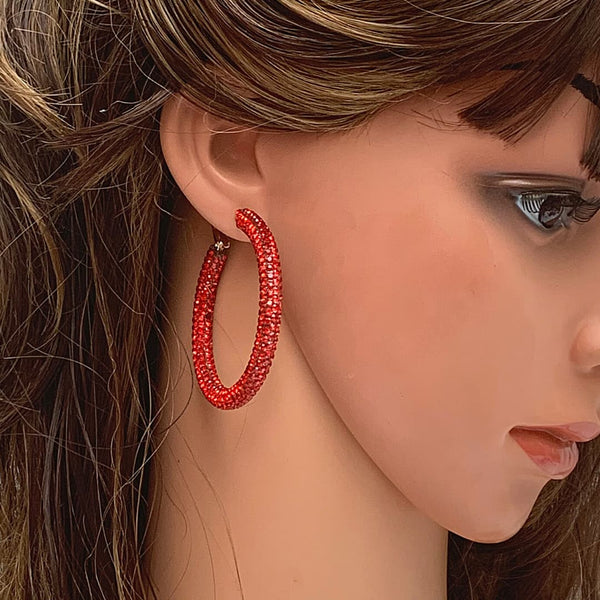 Side profile of a mannequin wearing sparkling red rhinestone hoop earrings, highlighting the 2-inch size and vibrant red stones.